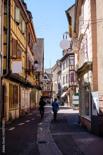 Gorgeous cobbled street in Colmar, Alsace, with people walking around during spring.