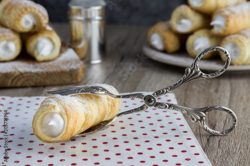 puff pastry creme rolle with cream (traditional Czech dessert) in a confectioner pliers