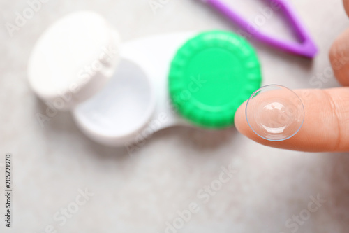 Woman holding contact lens over table, closeup