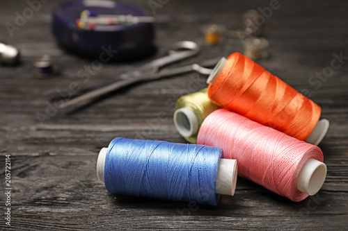 Sewing threads and accessories on wooden background