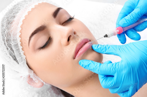 Young woman getting lip injection in beautician salon