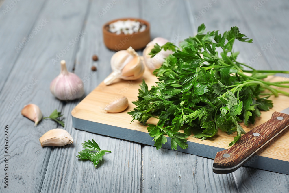 Board with fresh green parsley and garlic on table Board with fresh green parsley and garlic on table