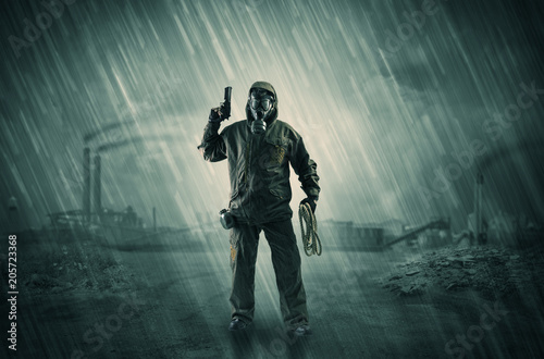 Gas masked survival man coming with arms on his hand  in a demolished dark environment 

