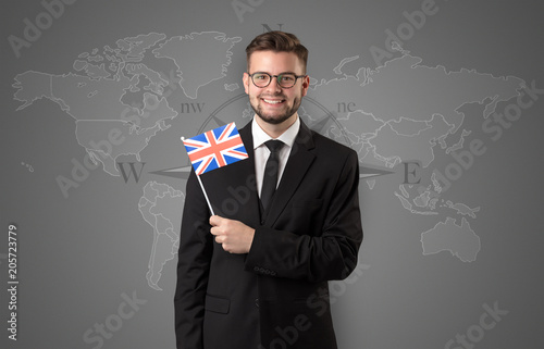 Cheerful businessman standing in front of a map with flag on his hand
