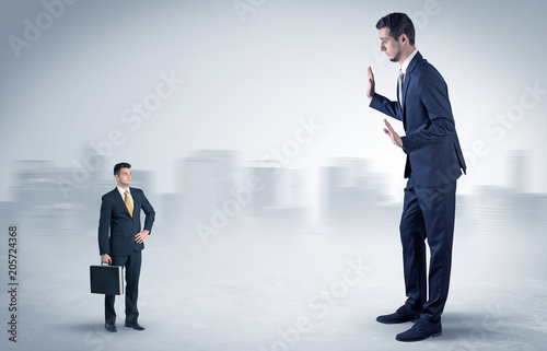 Giant businessman being afraid of small serious executor with suitcase 