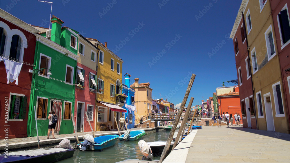 Many relaxed people strolling in colorful streets on Burano island, summer rest