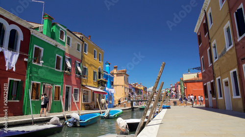 Many relaxed people strolling in colorful streets on Burano island, summer rest