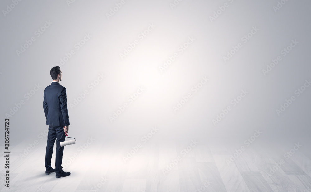 Man standing with his back in an empty room with object in his hand Man standing with his back in an empty room with object in his hand