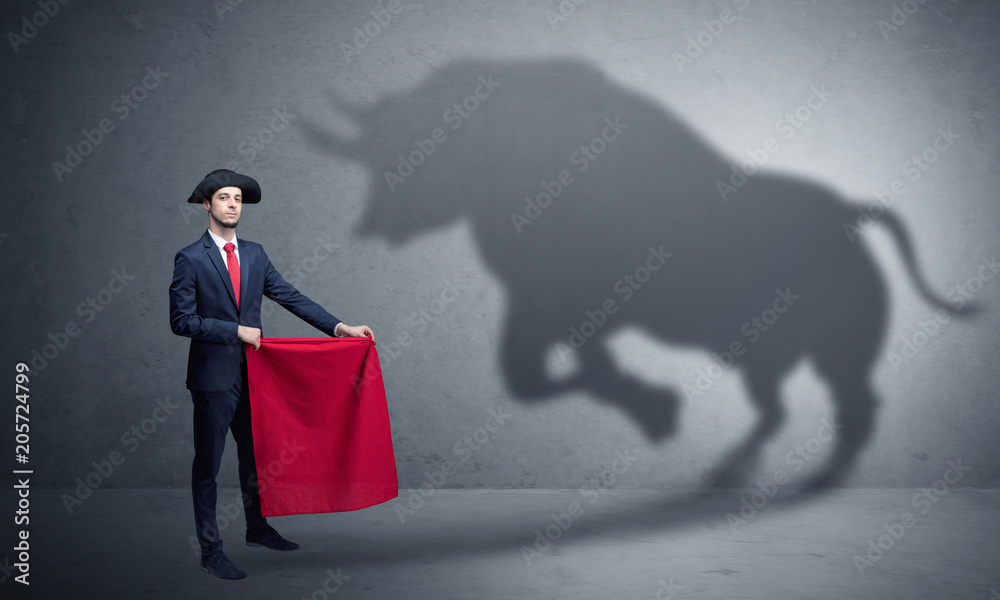 Businessman standing with red cloth in his hand and big bull shadow on the  wall Stock Photo