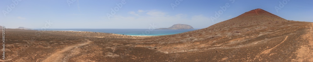 Panoramic view of Playa de las Conchas and volcanic crater under a cloudless blue sky. La Graciosa, Lanzarote, Canary Islands, Spain. Panoramic view of Playa de las Conchas and volcanic crater under a cloudless blue sky. La Graciosa, Lanzarote, Canary Islands, Spain.