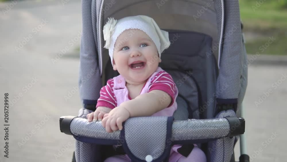 Little baby laughing, sitting in baby carriage, slowmotion, mediumshot Little baby laughing, sitting in baby carriage, slowmotion, mediumshot