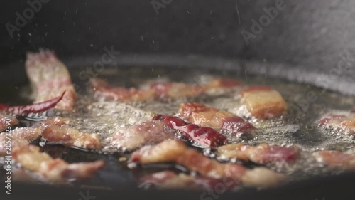 Bacon and chili sizzling in white wine in slow motion, camera pans left to right