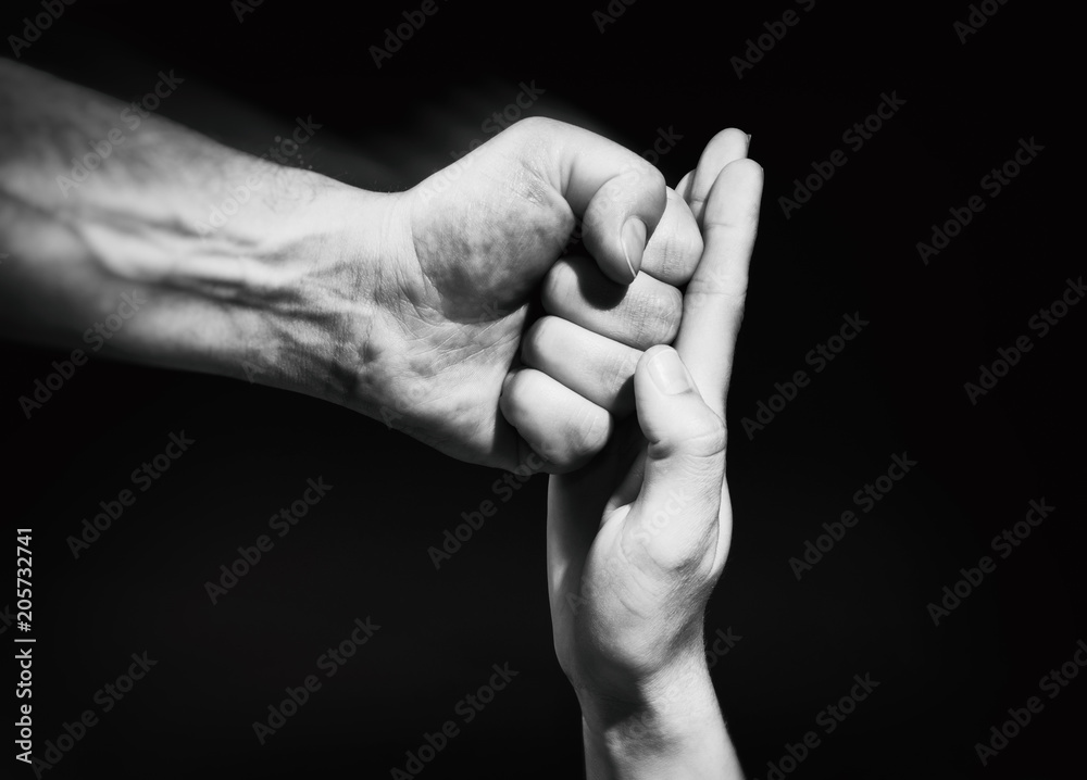 The female palm stops a male punch. The concept of protection of women's rights and gender equality. Black and white. The female palm stops a male punch. The concept of protection of women's rights and gender equality. Black and white.