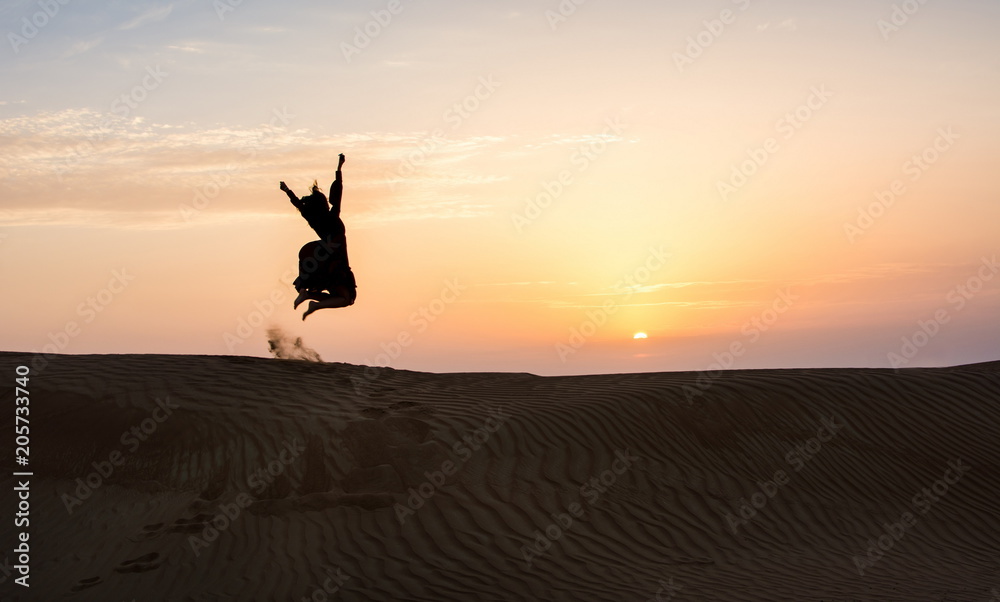 Silhouette of a woman jumping in the desert