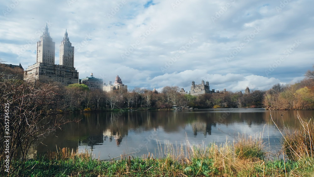 The San Remo View from Central Park at Manhattan, New York with lake, cloud sky, grass, and reflection.