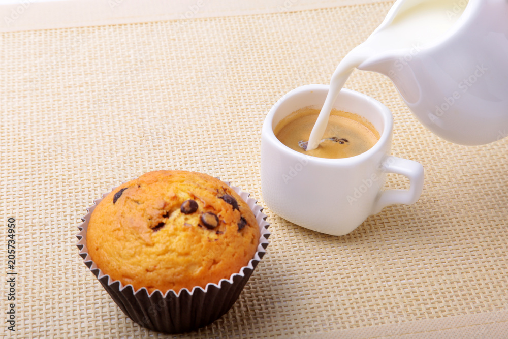 Perfect morning breakfast with Delicious homemade cupcakes with raisins, chocolate chips, espresso coffee in white cup and milk on textile background. Muffins. Perfect morning breakfast with Delicious homemade cupcakes with raisins, chocolate chips, espresso coffee in white cup and milk on textile background. Muffins.