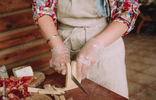 woman cuts meat hard cheese lobules board