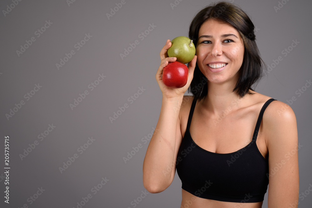 Young beautiful woman ready for gym against gray background Young beautiful woman ready for gym against gray background