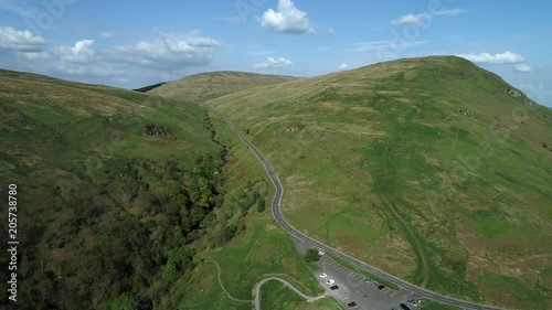 Aerial footage of the Crow Road over the Campsie Fells from Lennoxtown, flying over the Queensview car park and a picturesque wooded glen with waterfall. photo