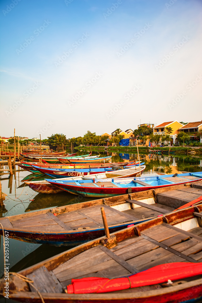 HOI AN, QUANG NAM, VIETNAM, April 26th, 2018: Boats by the river in ancient town Hoi An with view of typical yellow houses