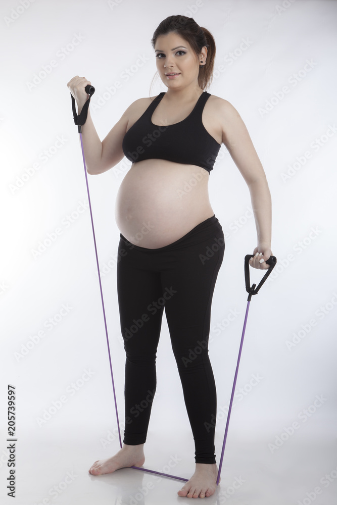 Pregnant woman doing gymnastic exercises on white background
