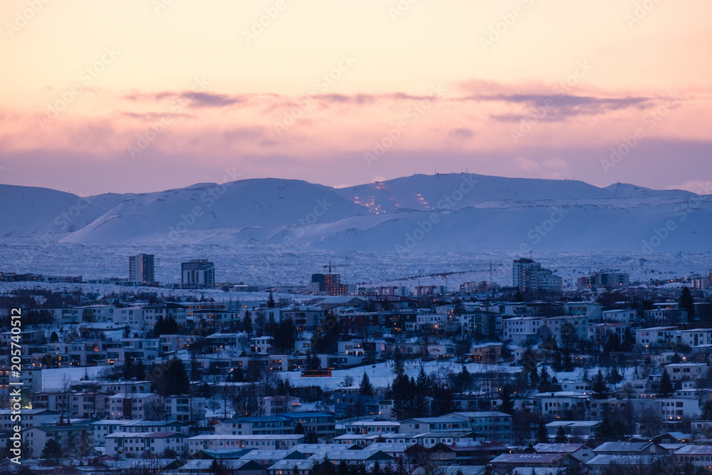 Early morning shot of modern urban development in Reykjavik, Iceland in front of snow covered mountains and fjords in winter.