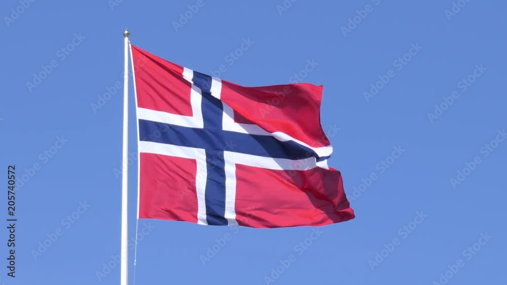 A Norwegian flag fluttering in the wind, set against a clear blue sky.