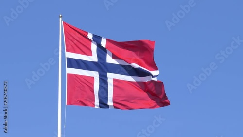 A Norwegian flag fluttering in the wind, set against a clear blue sky. photo