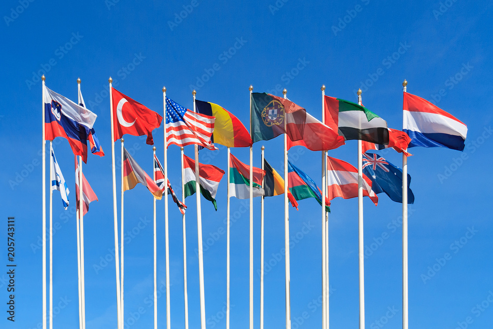 Flags of different countries of the world flutters in the wind a background of clear blue sky