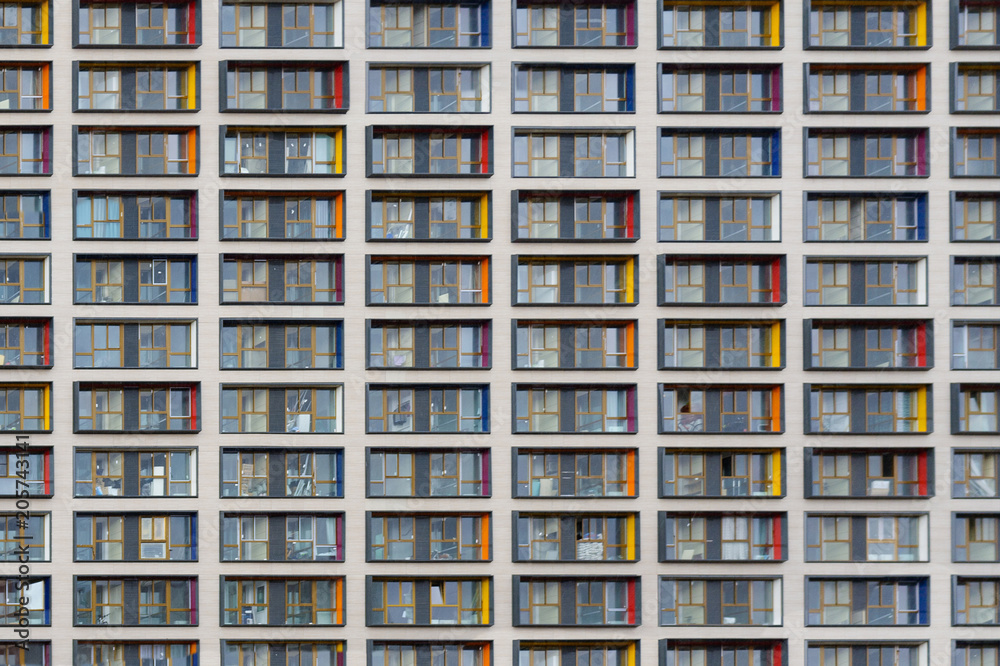Facade of modern building of concrete and glass with colored inserts on the windows as  texture, background, abstract
