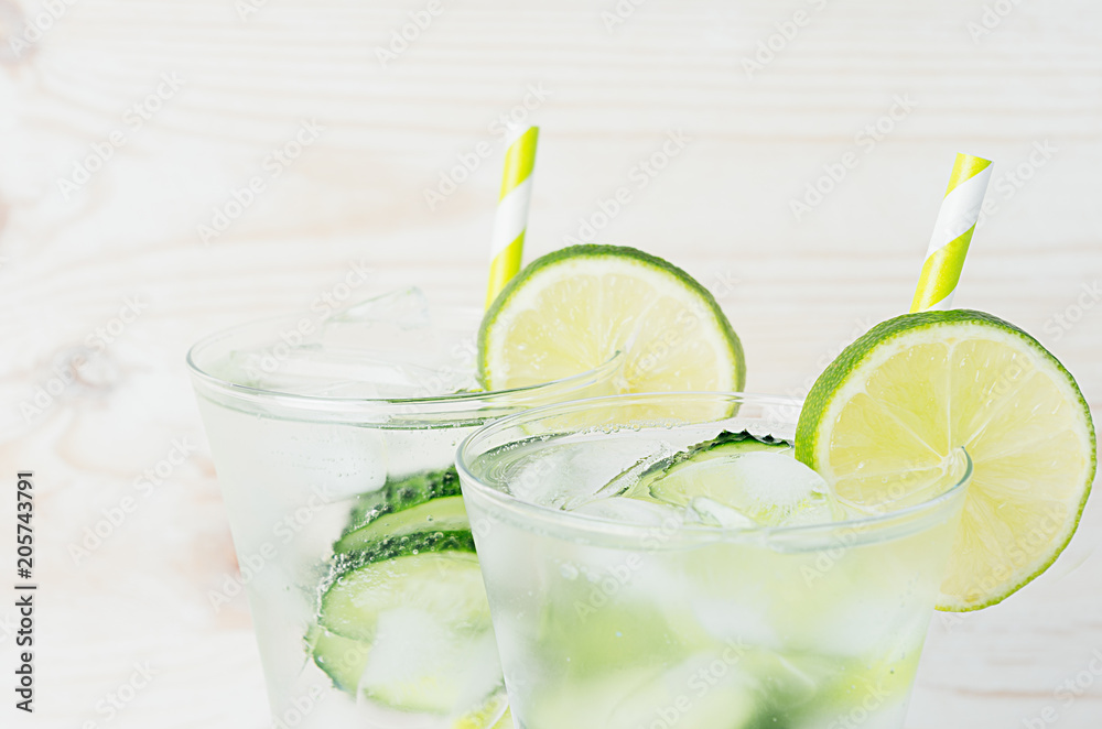 Fresh summer organic drink with slices cucumber, ice, lime, straw on white wood board, closeup. Fresh summer organic drink with slices cucumber, ice, lime, straw on white wood board, closeup.