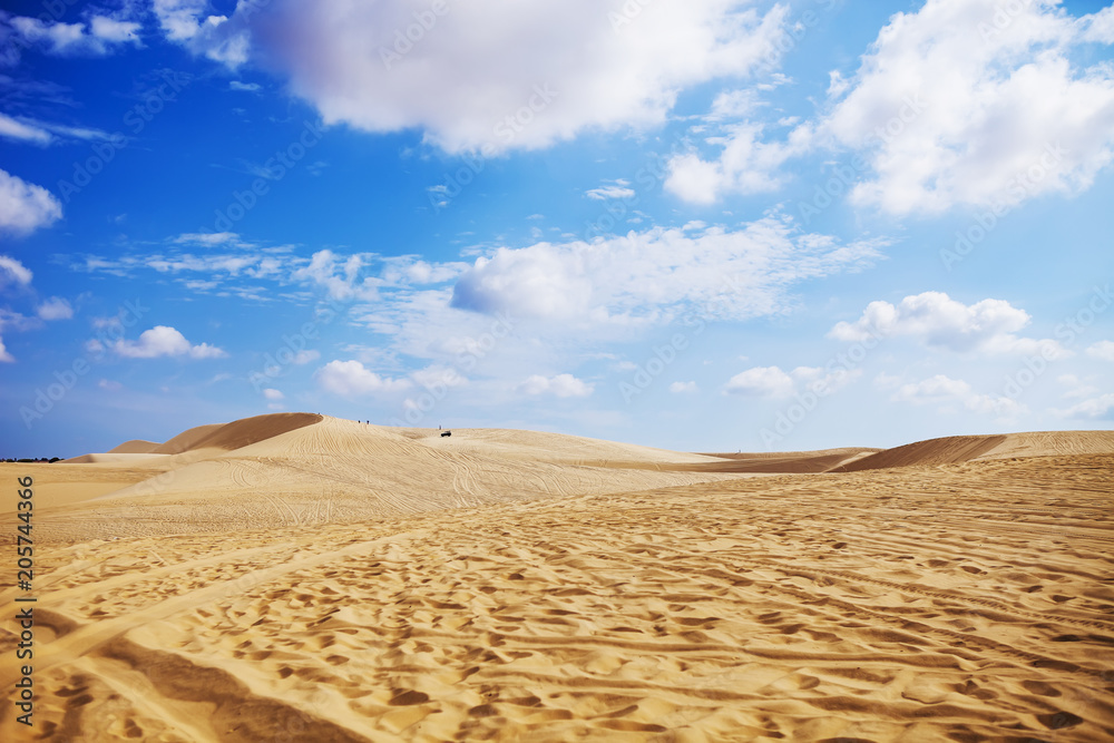 Sand dunes near Mui Ne. Group of off roads on top of dunes in the background. Sunny day with blue sky and clouds