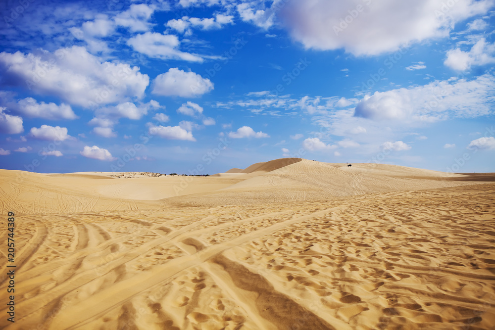 Sand dunes near Mui Ne. Group of off roads on top of dunes in the background. Sunny day with blue sky and clouds Sand dunes near Mui Ne. Group of off roads on top of dunes in the background. Sunny day with blue sky and clouds