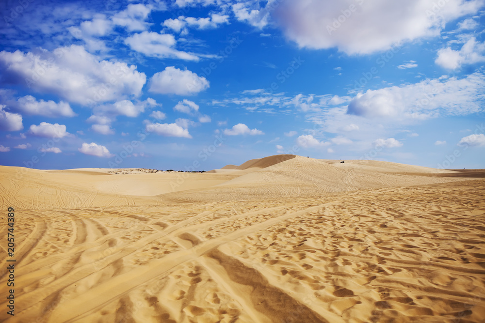 Sand dunes near Mui Ne. Group of off roads on top of dunes in the background. Sunny day with blue sky and clouds