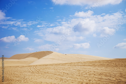 Sand dunes near Mui Ne. Group of off roads on top of dunes in the background. Sunny day with blue sky and clouds