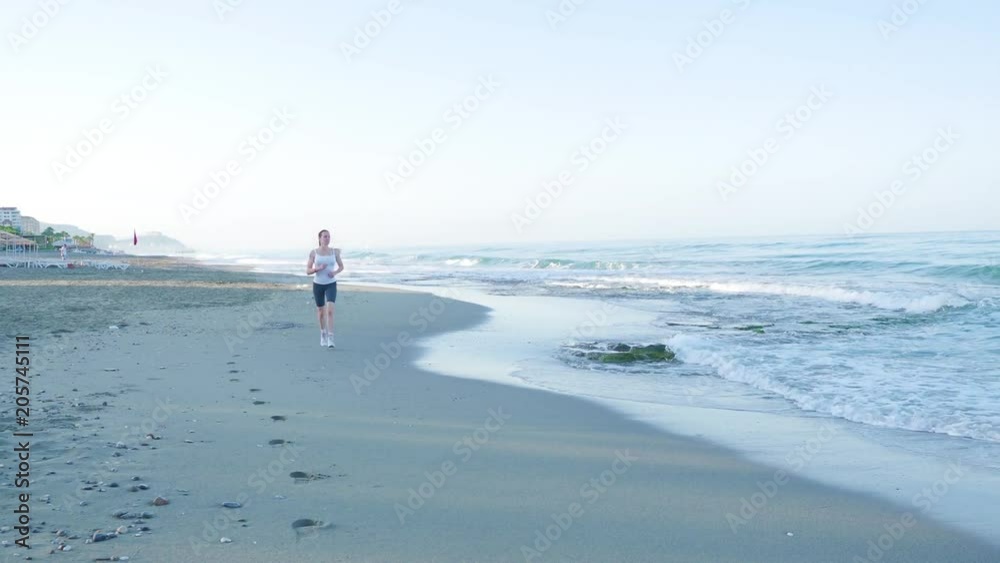 the girl is engaged in sports. She runs on the camera along the beach