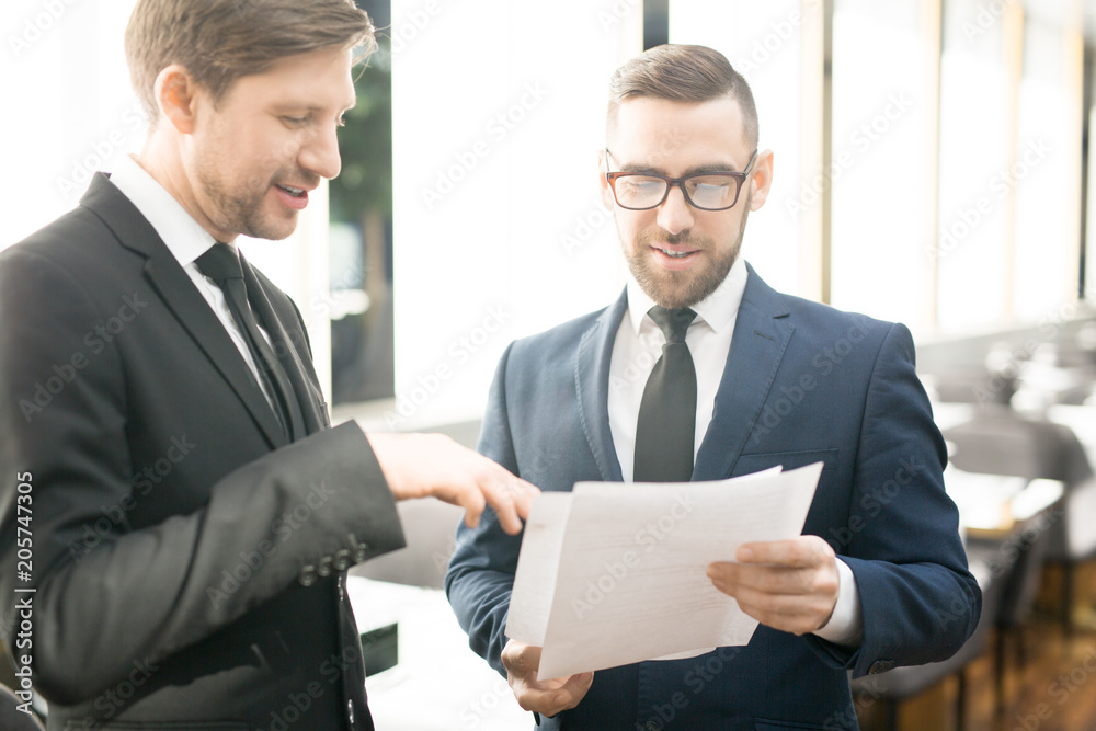 One of businessmen explaining some points on paper during discussion of new contract at meeting One of businessmen explaining some points on paper during discussion of new contract at meeting