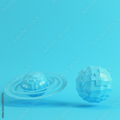 Fototapeta Naklejka Na Ścianę i Meble -  Two blue low poly planets on bright blue background in pastel colors