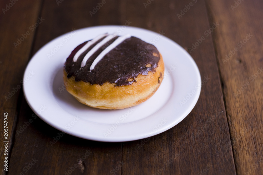 Choco Donut on a white plate and a wooden table Choco Donut on a white plate and a wooden table