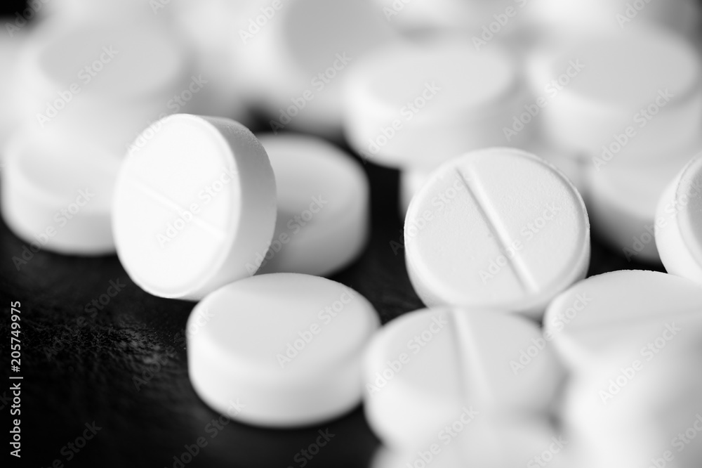 White pharmaceutical pills on a black background close up White pharmaceutical pills on a black background close up