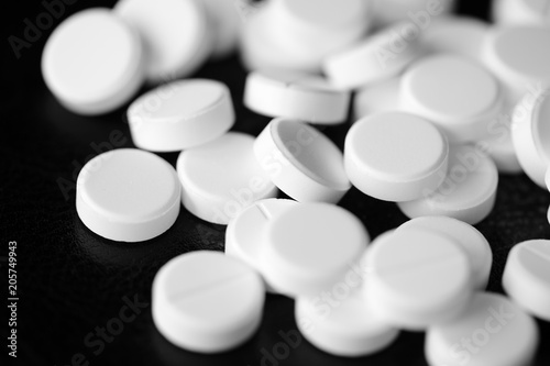 White pharmaceutical pills on a black background close up