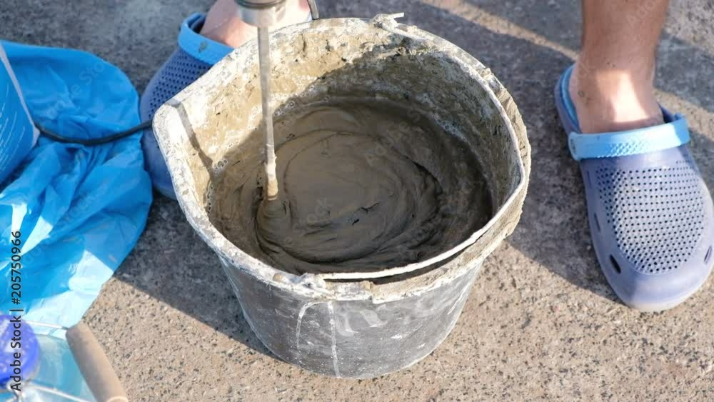 Close up shot of a builder mixing cement in a bucket on a constraction site with a special tools. Close up shot of a builder mixing cement in a bucket on a constraction site with a special tools.