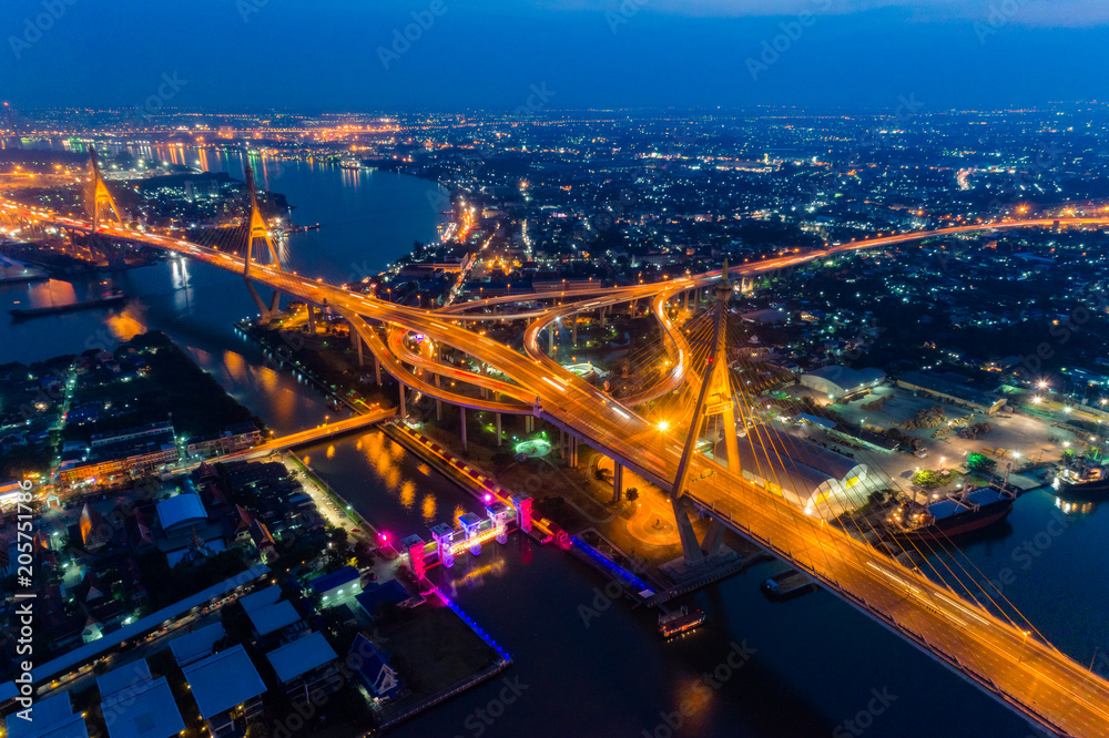 Aerial view of Bhumibol suspension bridge in Bangkok city with light trails of car on the road at sunset sky and clouds in Bangkok Thailand.