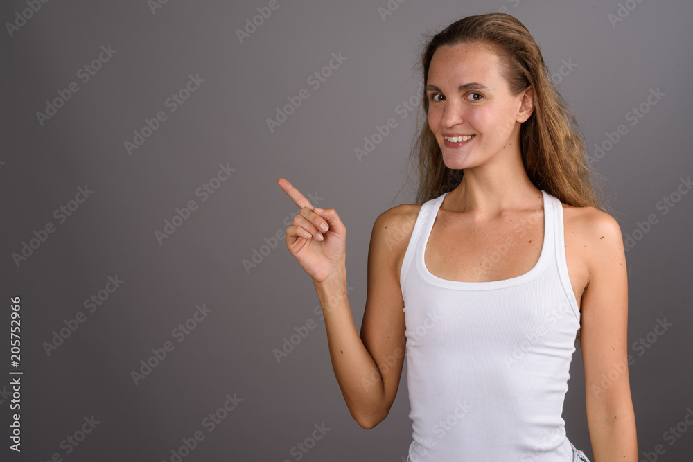 Young beautiful woman with long blond hair against gray backgrou Young beautiful woman with long blond hair against gray backgrou