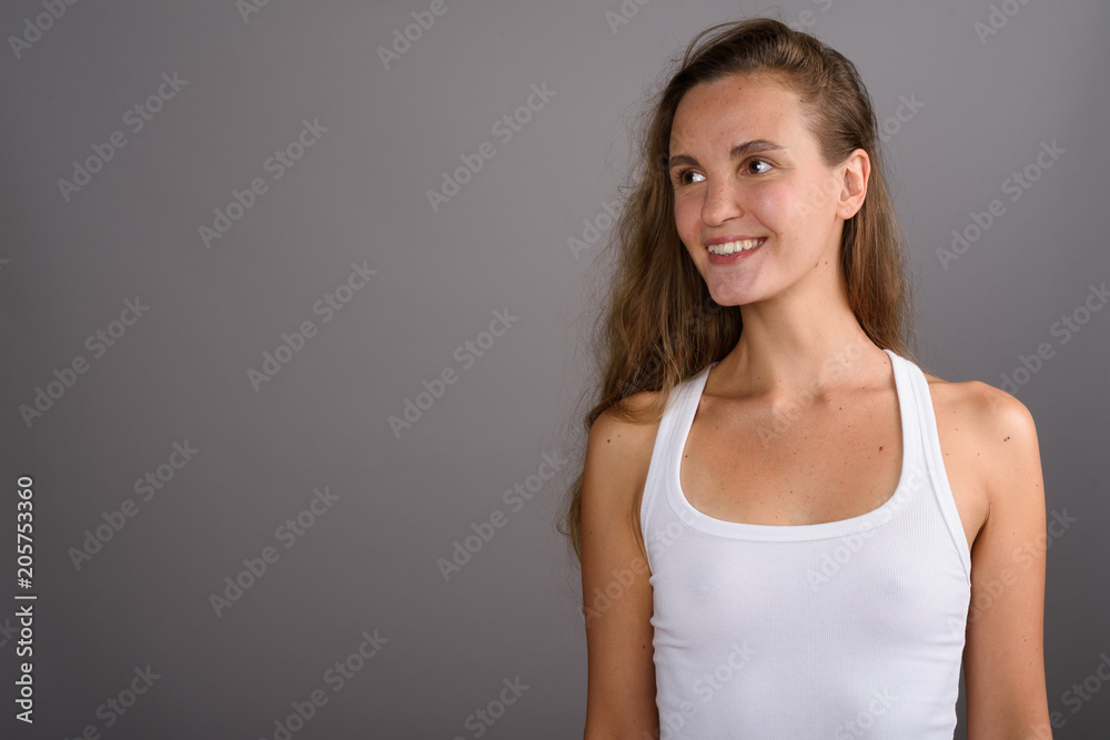 Young beautiful woman with long blond hair against gray backgrou Young beautiful woman with long blond hair against gray backgrou