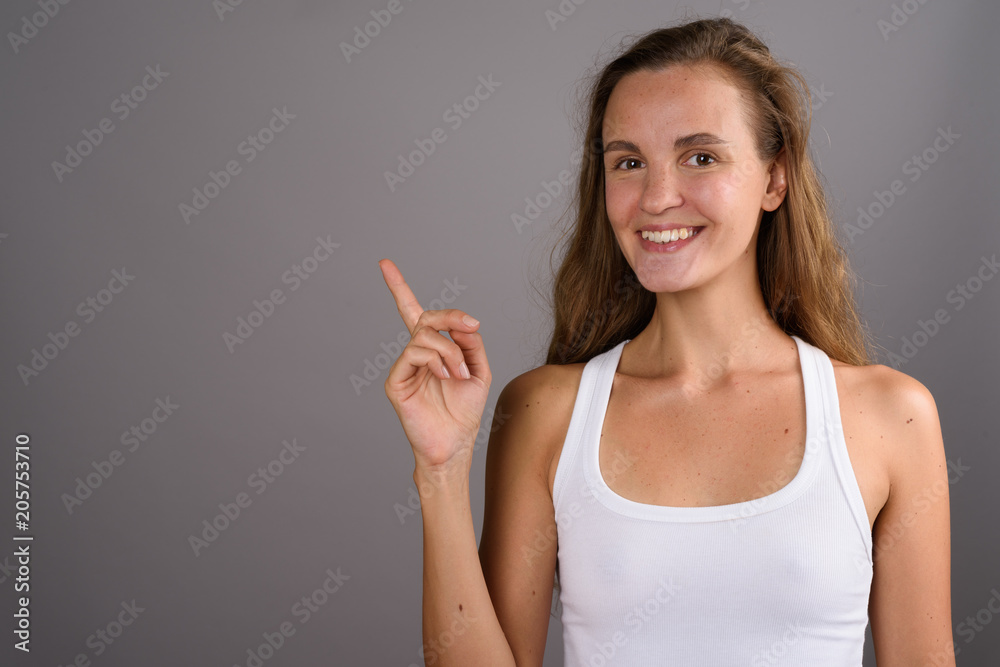 Young beautiful woman with long blond hair against gray backgrou Young beautiful woman with long blond hair against gray backgrou