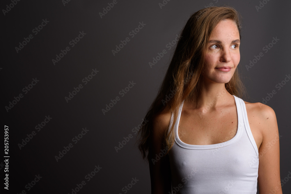 Young beautiful woman with long blond hair against gray backgrou Young beautiful woman with long blond hair against gray backgrou