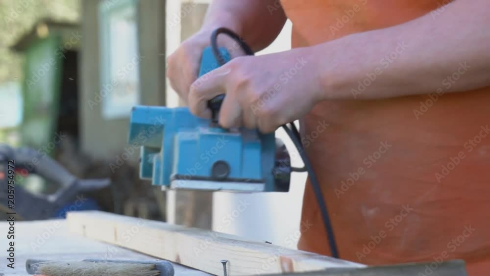 Handyman using electric wood planer outdoors. Handyman using electric wood planer outdoors.