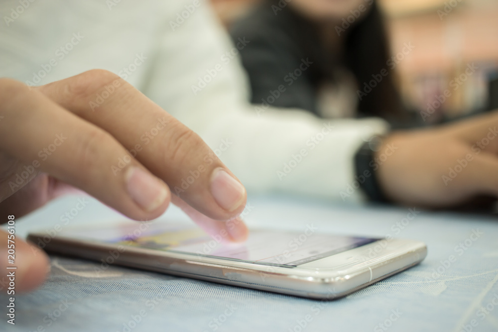 Fototapeta premium Online searching social networks by Smartphone Concept: Hand of young man pointing finger on blank screen smart phone, using hand clean gadget or typing sms message to his friends on table background
