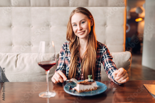 Woman in cafe, sweet cake and wine on the table